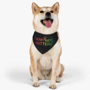 tan and white dog with triangular, black bandanna around its neck showing the rainbow colored Happiness Matters logo